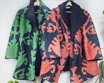 May include: Two long-sleeved jackets with a black fleece lining. One jacket is green with a black floral pattern, and the other is orange with a black floral pattern.