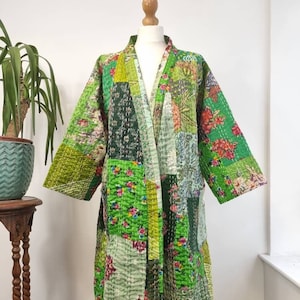 May include: A green patchwork quilted robe with a floral print. The robe has a long, flowing silhouette and a wide, open collar. It is made of a soft, comfortable fabric and is perfect for lounging around the house.