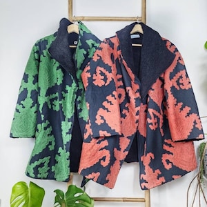 May include: Two long-sleeved jackets with a black fleece lining. One jacket is green with a black floral pattern, and the other is orange with a black floral pattern.