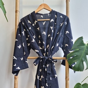 May include: A black and white patterned robe with a white bird design. The robe is hanging on a wooden ladder.