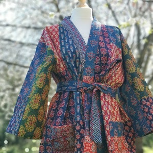 May include: A blue and red patchwork quilted robe with a long sleeve and a tie belt.