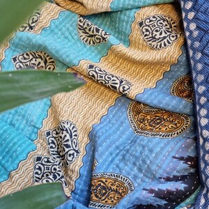 May include: A blue and gold kantha quilt with a paisley pattern. The quilt is made from recycled saris and is hand-stitched.