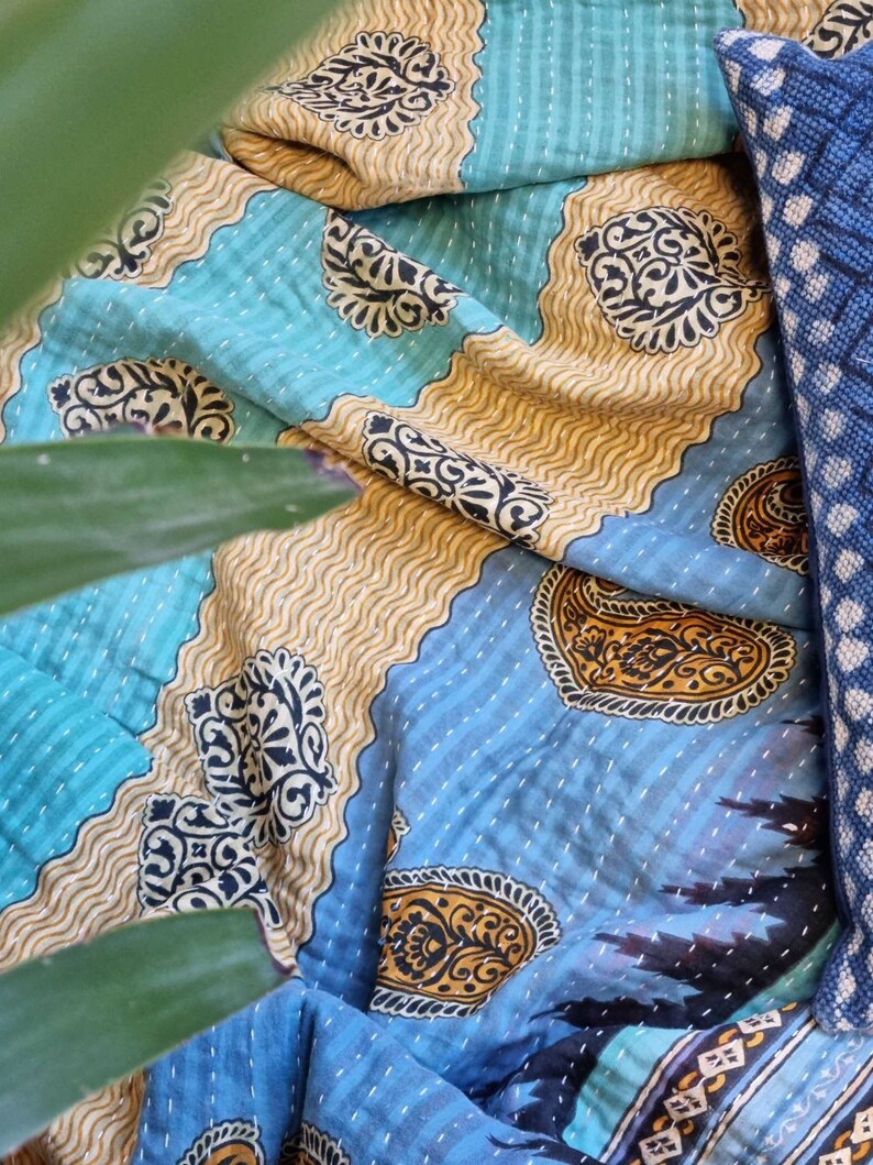 May include: A blue and gold kantha quilt with a paisley pattern. The quilt is made from recycled saris and is hand-stitched.