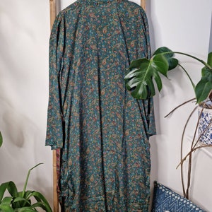 May include: A long-sleeved robe featuring a dark teal base color with an intricate, multi-colored paisley pattern in shades of gold, red, and blue. The garment has a classic collar, a button-down front, and a loose, flowing silhouette.