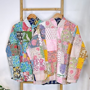 May include: Two colorful patchwork jackets with a quilted design. The jackets have a mandarin collar and a button closure. The jackets are hanging on a wooden rack.