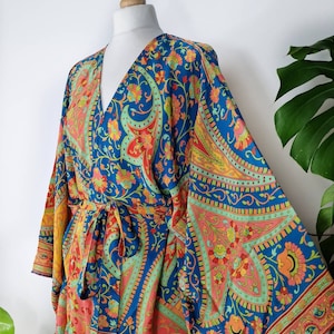May include: A blue and orange patterned kimono with long sleeves and a tie belt. The kimono features a paisley design with floral accents.