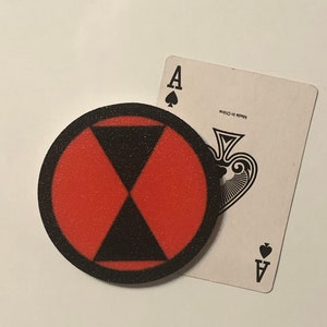 Op de afbeelding: Een rond, rood en zwart, militair stijl, fallout shelter-bord met de tekst "Made in China" op een witte speelkaart met een zwarte schoppen aas.
