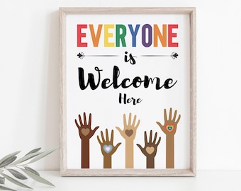 May include: A white framed print with the text "EVERYONE is Welcome Here" in black lettering. The text "EVERYONE" is in rainbow colors. Five raised hands with different skin tones are shown below the text, each with a heart in the palm of their hand. The hearts are different colors.