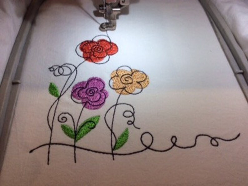 May include: Embroidered design of four stylized flowers in orange, purple, yellow, and green on a white fabric background.