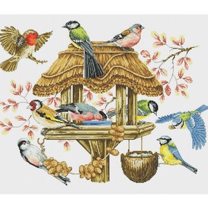 May include: A wooden bird feeder with a thatched roof, surrounded by a variety of colorful birds, including bluebirds, goldfinches, and chickadees. The feeder is filled with seeds and has a small dish for water.