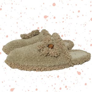 May include: A pair of beige fuzzy slippers with a decorative button on the top. The slippers have a fluffy trim around the edges.