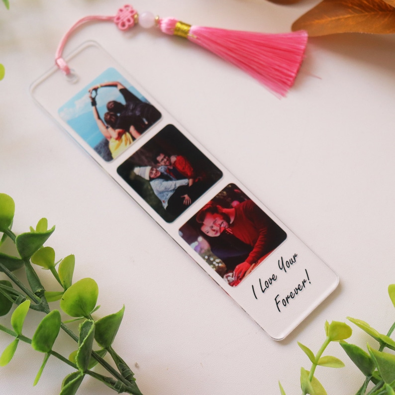 May include: A clear acrylic bookmark with three square photo slots. The photos show a group of people, a couple, and a single person. The bookmark has the text "I love you forever!" written on it.