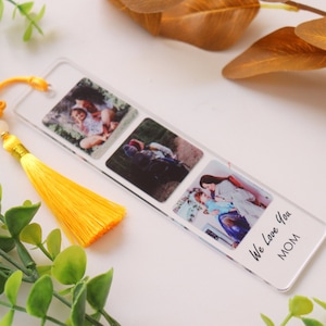 May include: A clear acrylic bookmark with three photo slots and a yellow tassel. The bookmark has the text "We Love You MOM" printed on the bottom.