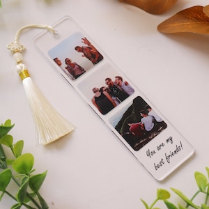 May include: A clear acrylic bookmark with three square photo inserts featuring a group of friends. The bookmark has a white tassel attached and the text "You are my best friends!" printed on the bottom.