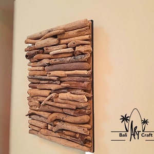 May include: A square wall art piece made of driftwood arranged in a layered pattern. The driftwood is a variety of shades of brown and beige. The piece is mounted on a black background.