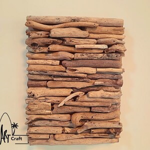 May include: A wall art piece made of driftwood arranged in a layered pattern. The driftwood is a natural light brown color and has a rustic, weathered look.
