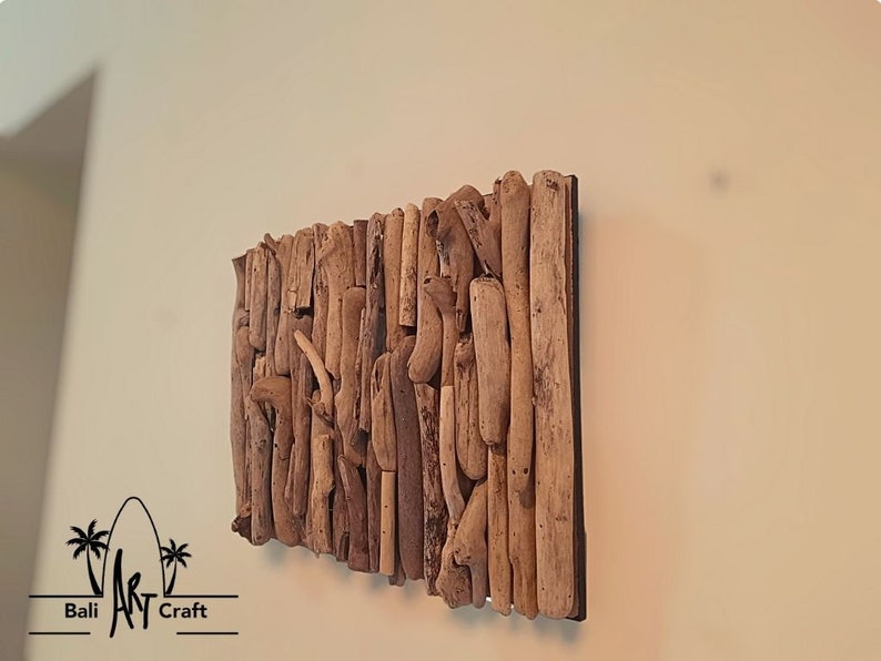 May include: A wall art piece made of driftwood arranged in a rectangular shape. The driftwood is a variety of shades of brown and beige. The piece is mounted on a black background.