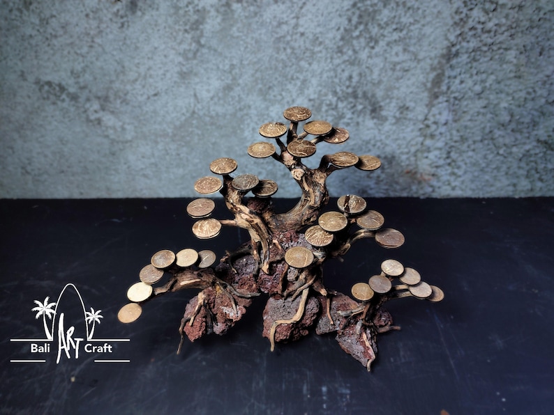 Puede incluir: Escultura de bons&aacute;i artesanal hecha de madera natural y monedas de metal. El &aacute;rbol presenta un tronco y ramas detallados con hojas en forma de moneda. La escultura se encuentra sobre un fondo oscuro, mostrando los intrincados detalles de la obra.