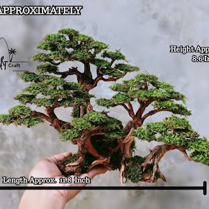 Puede incluir: Un bons&aacute;i en miniatura con un tronco y ramas marrones texturizados, cubiertos de follaje verde vibrante. La altura del &aacute;rbol es de aproximadamente 21,8 cm y la longitud es de aproximadamente 30 cm. El texto "Bali Art Craft" es visible.
