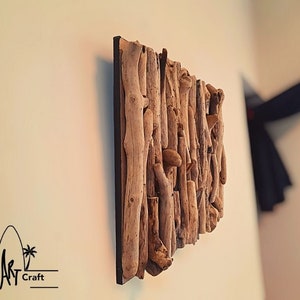 May include: A wall art piece made from driftwood, arranged in a vertical pattern. The wood is a natural brown color and has a rough texture. The piece is mounted on a black background.