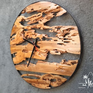 May include: A round wooden clock with a black metal frame. The clock face is made of natural wood with a unique, organic pattern. The clock hands are black.