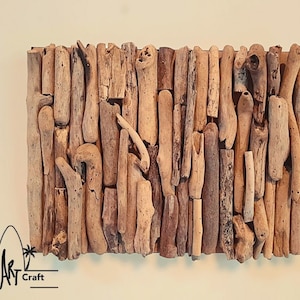 May include: A wall art piece made of driftwood arranged in a vertical pattern. The driftwood is a variety of shades of brown and beige. The piece is mounted on a wooden backing.