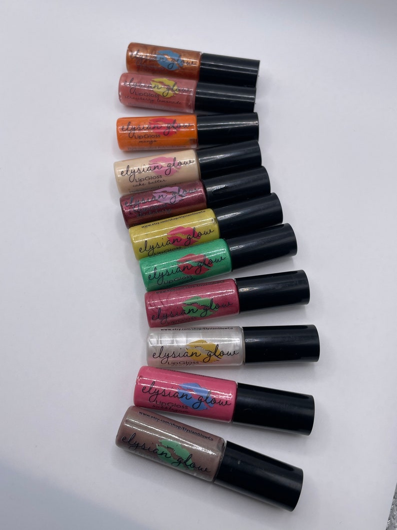 Puede incluir: Un conjunto de diez frascos peque&ntilde;os de brillo de labios en varios colores, incluyendo naranja, amarillo, verde, rosa y marr&oacute;n. Cada frasco tiene una tapa negra y una etiqueta que dice "elysian glow" y "lip gloss".