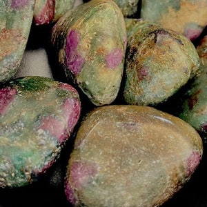 May include: A collection of green and pink tumbled stones with a rough, natural texture. The stones have a mottled appearance with shades of green, pink, and brown.