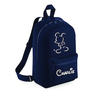 May include: A navy blue backpack featuring a white outline of Mickey Mouse and the name "Charlie" in white script. It has a zipped main compartment, a front zipped pocket, and adjustable shoulder straps.