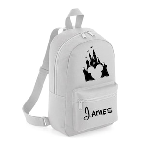 May include: A grey canvas backpack featuring a black silhouette of the Disney castle and Mickey Mouse ears. The backpack has a zipped pocket on the front and the name "James" is printed below the image.