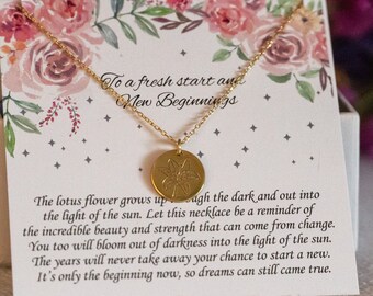 May include: A gold necklace with a lotus flower pendant and a card that reads "To a fresh start and New Beginnings." The card has a floral design and the text "The lotus flower grows up through the dark and out into the light of the sun. Let this necklace be a reminder of the incredible beauty and strength that can come from change. You too will bloom out of darkness into the light of the sun. The years will never take away your chance to start a new. It's only the beginning now, so dreams can still come true."