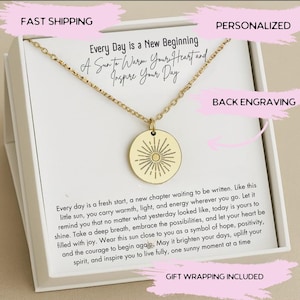 May include: Gold-colored necklace with a round pendant featuring a sunburst design. The pendant hangs from a delicate chain. The text on the card reads "Every Day is a New Beginning, A Sun to Warm Your Heart and Inspire Your Day."