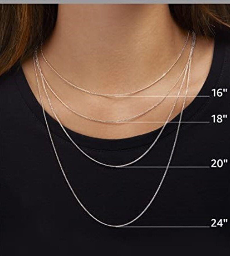 Op de afbeelding: Vier zilveren kettingen in verschillende lengtes, 16 inch, 18 inch, 20 inch en 24 inch, worden getoond op een model dat een zwart shirt draagt.