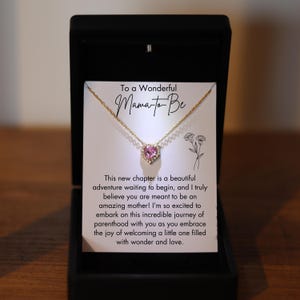 Könnte beinhalten: Eine goldene Halskette mit einem rosa Herz-Anhänger und einer Karte mit der Aufschrift "An eine wundervolle werdende Mama. Dieses neue Kapitel ist ein wunderschönes Abenteuer, das beginnt, und ich glaube wirklich, dass du dazu bestimmt bist, eine großartige Mutter zu sein! Ich freue mich so sehr, diese unglaubliche Reise der Elternschaft mit dir zu beginnen, während du die Freude genießt, ein kleines Wesen voller Wunder und Liebe willkommen zu heißen."