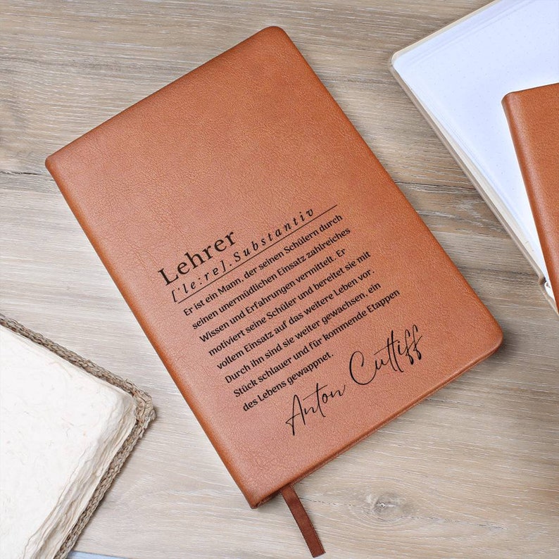 May include: A brown leather journal with the word "Lehrer" defined as a noun in German. The definition is engraved on the front cover. The name "Anton Cuttiff" is also engraved on the cover.