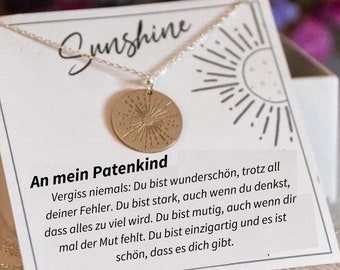 May include: A silver necklace with a gold sun-shaped pendant. The pendant has a textured surface and a small circle in the center. The necklace is displayed on a white card with the text "Sunshine" and a message about being strong and unique. The message reads: "An mein Patenkind Vergiss niemals: Du bist wunderschön, trotz all deiner Fehler. Du bist stark, auch wenn du denkst, dass alles zu viel wird. Du bist mutig, auch wenn dir mal der Mut fehlt. Du bist einzigartig und es ist schön, dass es dich gibt."