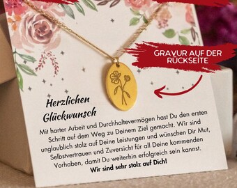 May include: A gold-colored necklace with a floral pendant, displayed on a card with floral accents and German text. The pendant is oval-shaped with a flower design. The card has the words "Herzlichen Glückwunsch".