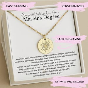 May include: A gold necklace with a sunburst pendant in a white gift box. The box has a pink background with the text "Congratulations On Your Master's Degree" and "Personalized" and "Back Engraving". The text "Gift Wrapping Included" is at the bottom of the box.