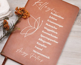 May include: A brown leather journal with a white butterfly design and the text "Kolleg*in" and a list of positive attributes, including "Problemloser", "Zuhörer", "Krisenmanager", "Mutmacher", "Weggefährte", "Kummerkasten", "Sparringspartner", "Alltagsretter", "Komplize", "Freund", and "Herzensmensch". The name "Angy Peters" is also written in white on the bottom of the journal.