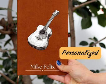 May include: A brown leather journal with a black and white illustration of an acoustic guitar. The journal has the text "Mike Felix" printed on the front.