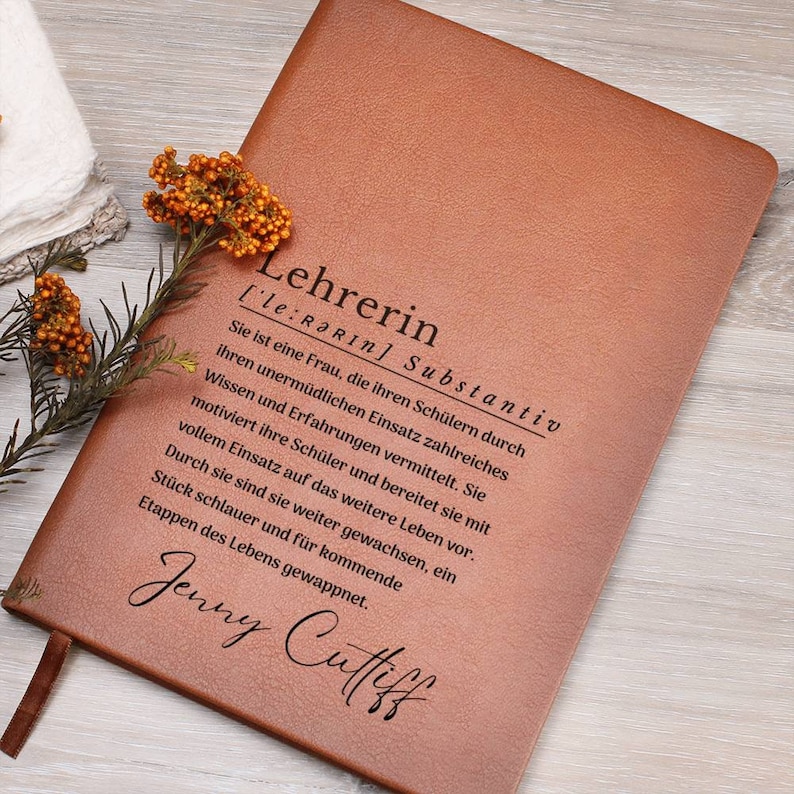 May include: A brown leather journal with the word "Lehrerin" engraved on the front. The word is defined as a noun and the definition is in German. The name "Jenny Cuffiff" is also engraved on the front.