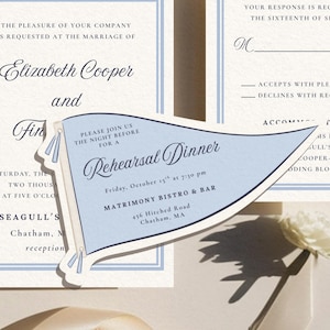 May include: Elegant wedding invitation suite with a light blue and white color scheme. The suite includes an invitation, RSVP card, and a rehearsal dinner announcement in a flag shape. The text includes names, dates, and locations.