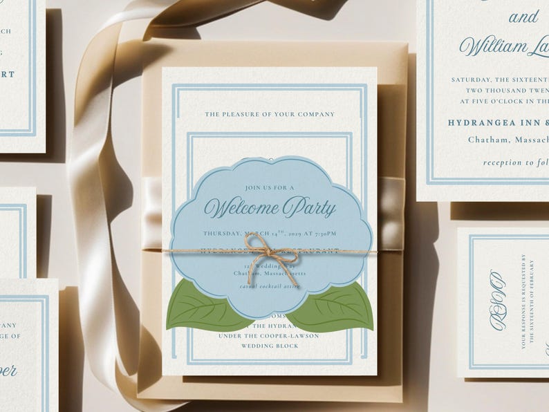 May include: Wedding invitation suite featuring a central invitation card with a light blue cloud-shaped design and the words "Welcome Party." The invitation is tied with twine and rests on a cream-colored envelope. Additional cards are visible.