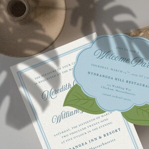 May include: Wedding invitation suite featuring a welcome party invitation in a cloud shape with green leaf accents. The invitation is light blue with elegant script. A second invitation with blue border is also visible.