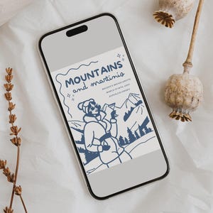 May include: A phone screen displaying a blue and white illustration of a woman in a winter coat holding a martini glass. The text reads "MOUNTAINS and martinis" and "Brooke's Bachelorette March Ninth, 2023 Breckenridge, Colorado".