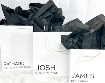 May include: Three white gift bags with black tissue paper inside. The bags are labeled with the names "Richard, Father of the Bride", "Josh, Groomsman", and "James, Best Man".