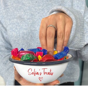 May include: A white enamel bowl with a navy blue rim, filled with colourful wrapped sweets. The bowl has the text "Sofia's Treats" in red script with a heart symbol. A hand reaches into the bowl.