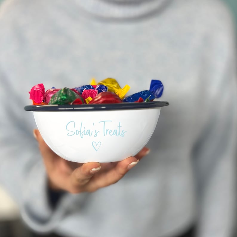 May include: White enamel bowl with a navy blue rim filled with colourful wrapped sweets. The bowl has the text "Sofia's Treats" in light blue script with a heart symbol below.