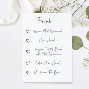 May include: A white card with the word "Finish" written in black cursive. Below the word "Finish" are five bullet points with hearts next to them. Each bullet point describes a feature of a product, such as "Luxury Matt Laminated", "Rope Handle", "200gsm Coated Board with Matt Lamination", "Cotton Rope Handle", and "Reinforced Top Base".