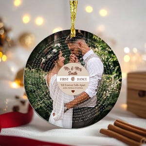 Puede incluir: Adorno navideño redondo con foto de una pareja. El adorno tiene el texto "Mr & Mrs Smith" y "First Dance" con la letra de la canción "Till Forever Falls Apart" de AMEIL FINNEAS O'CONNELL. Se adjunta una cinta dorada para colgar.